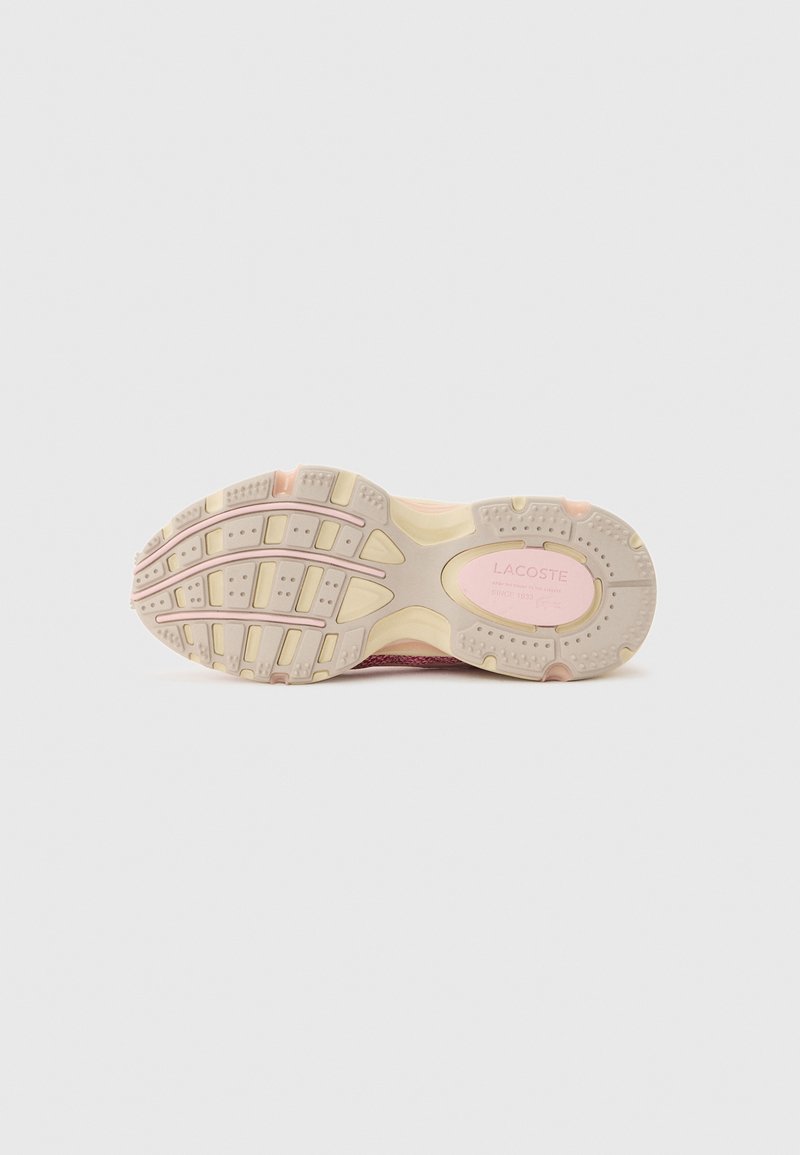 Sole of a pink and beige Lacoste sneaker with textured grip patterns and logo detail on the heel area.