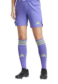 Paarse voetbalshorts met 3-strepenaccenten in neon groen, gecombineerd met bijpassende kniehokken met strepen en logo. Zwarte voetbalschoenen.