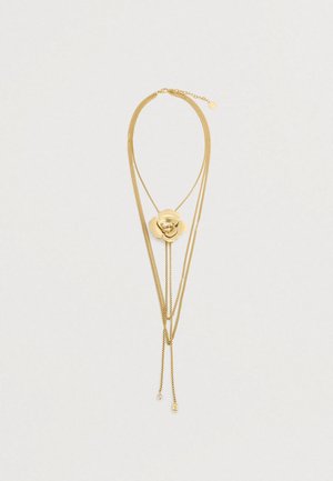 Χρυσό επιχρυσωμένο κολιέ που διαθέτει μια κεντρική διακόσμηση με φλοράλ σχέδιο, με υφασμάτινα πέταλα και λεπτές αλυσίδες, οι οποίες καταλήγουν σε ευαίσθητες λεπτομέρειες.