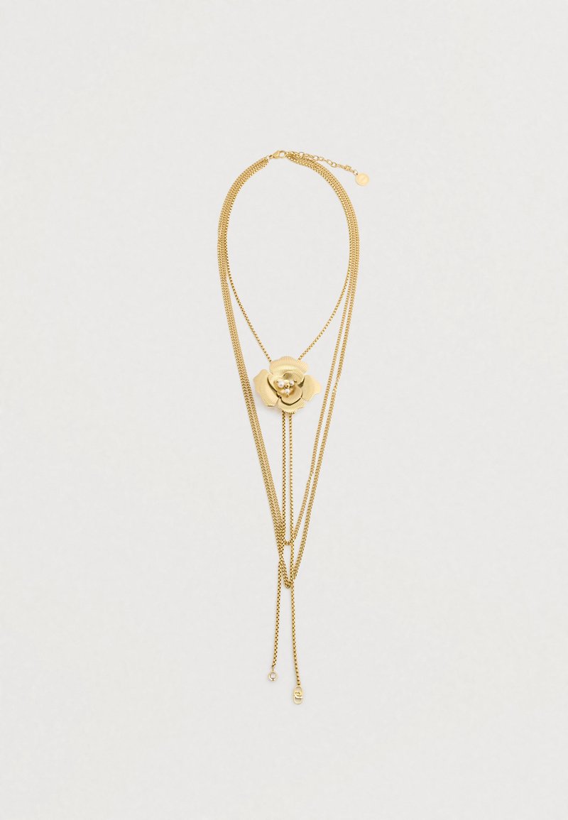 Χρυσό επιχρυσωμένο κολιέ που διαθέτει μια κεντρική διακόσμηση με φλοράλ σχέδιο, με υφασμάτινα πέταλα και λεπτές αλυσίδες, οι οποίες καταλήγουν σε ευαίσθητες λεπτομέρειες.