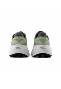 Une paire de chaussures de course New Balance grises et vert clair vue de l'arrière, montrant des semelles intermédiaires blanches étiquetées "Fresh Foam."