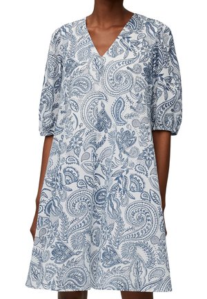 Weißes Kleid mit blauem Paisley- und Blumenmuster, V-Ausschnitt und ellbogenlangen Puffärmeln, getragen von einer dunkelhäutigen Person.