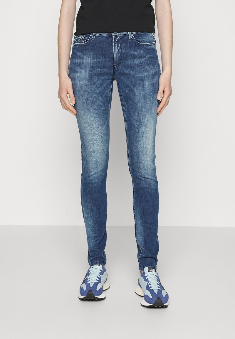Vaqueros de mezclilla en azul oscuro, con un ajuste slim, detalles desgastados en los muslos, diseño de cinco bolsillos y una clásica cremallera con cierre de botón.