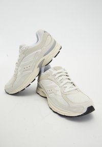 Scarpe da corsa leggere in mesh e suede color off-white, con un intersuola ammortizzata e una suola in gomma con un accento nero.