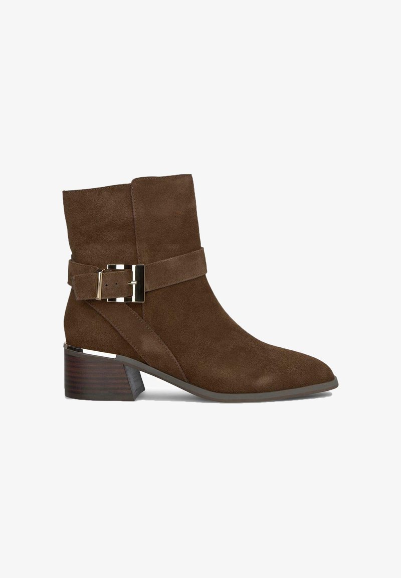 Bottes chevilles en daim marron avec un bout pointu, une boucle décorative et un talon moyen avec une finition en bois. Accentué par une large sangle.
