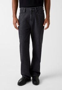Donkergrijze spijkerbroek met een relaxte pasvorm en rechte pijpen. Voorzien van steekzakken aan de voorkant, een knoopsluiting en subtiele stikseldetails.