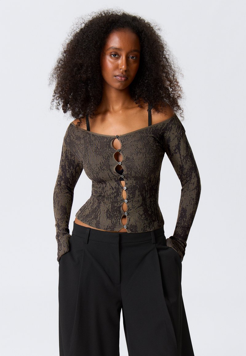 Off-the-shoulder, fitted top in black and gold pattern, featuring seven decorative buttons down the front and long sleeves.