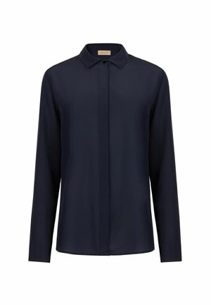 Marineblaue Bluse mit langen Ärmeln, spitzem Kragen und verdeckter Knopfleiste, dargestellt vor weißem Hintergrund.