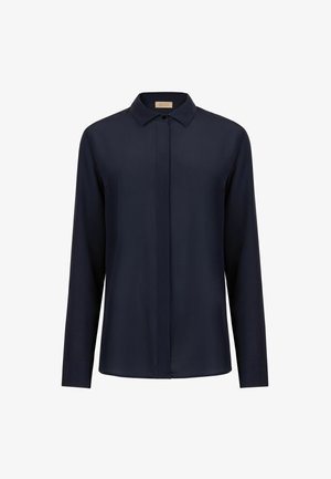 Marineblaue Bluse mit langen Ärmeln, spitzem Kragen und verdeckter Knopfleiste, dargestellt vor weißem Hintergrund.