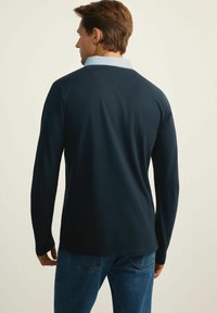 Granatowa koszula z długim rękawem z jasnoniebieskim kołnierzykiem, wykonana z miękkiego materiału. Charakteryzuje się luźnym krojem i subtelnymi szwami na kołnierzyku.