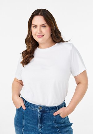 Balta trumpomis rankovėmis marškinėliai, pagaminti iš lygaus medvilninio audinio, derinami su aukštu liemeniu mėlynais džinsais, turinčiais priekinės kišenes ir mygtuko užsegimą.