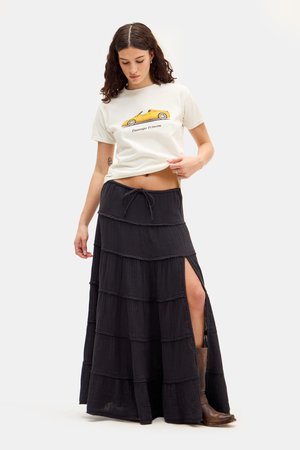Gonna nera maxi a strati con spacchi laterali, realizzata in tessuto texturizzato. Abbinata a una t-shirt color crema con una grafica di design auto.