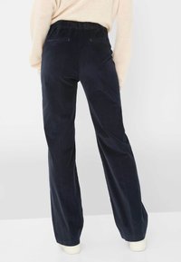 Pantaloni in corduroy blu navy con gamba ampia, vita elastica e due tasche posteriori, che mostrano una texture liscia e un design sartoriale.