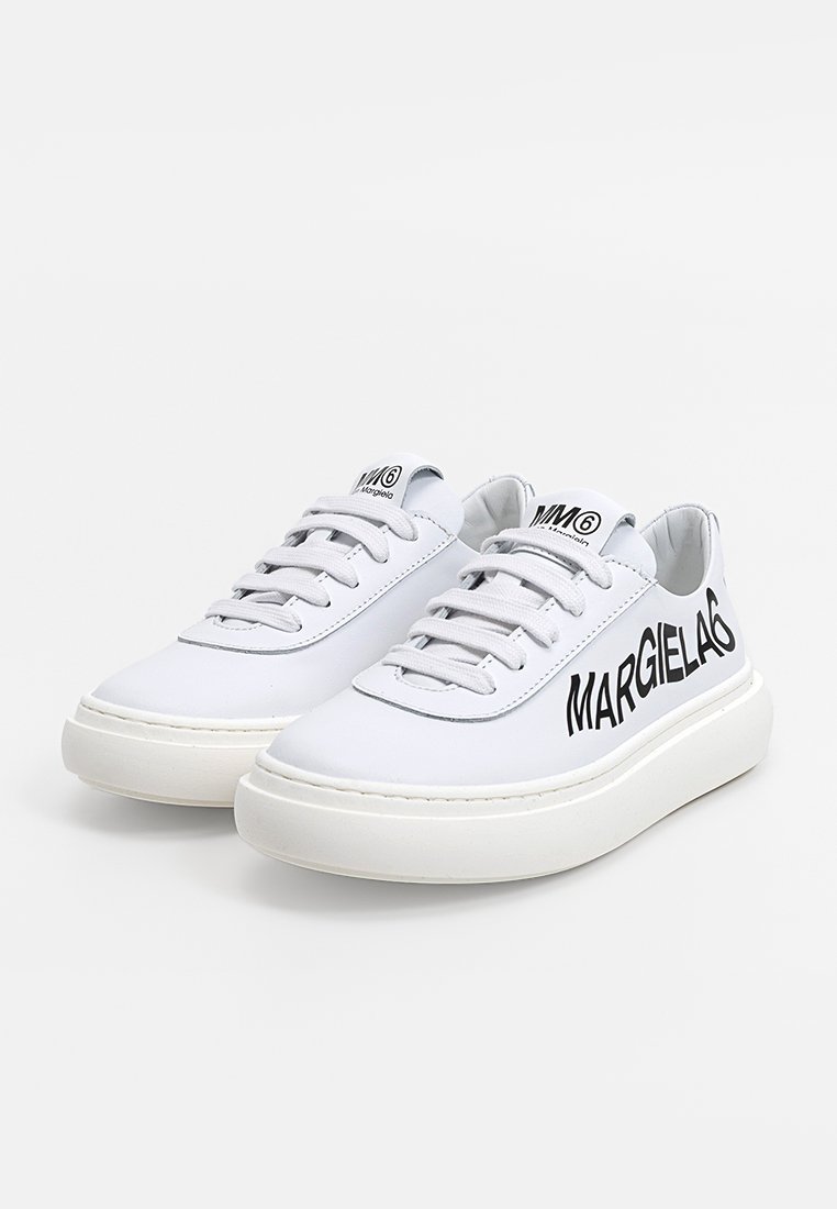Sneaker in pelle bianca con suola piatta, dotate di lacci tonali e di un evidente logo nero "MARGIELA" sul lato. Design minimalista.