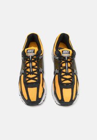 Baskets de course Nike avec un dessus en mesh jaune, des accents noirs et une semelle blanche. Comprend des lacets, un logo sur la languette et un col rembourré.