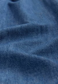 Denimstoff in tiefblau, mit einer glatten Textur und leichten Variationen, die subtile gewebte Muster und ein sanftes Drapierungsaussehen zeigen.