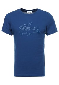 Blå bomullst-shirt med kort ärm som har en texturerad krokodil-logotyp på framsidan, rund hals och standard passform.