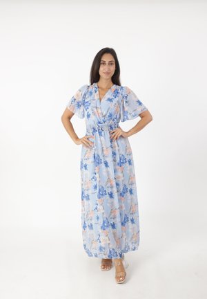 Maxi-jurk van lichtblauwe stof met bloempatronen in roze en blauw. Korte, geborduurde mouwen en een strakke taille. Doorzichtige hakken.
