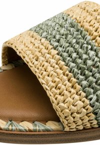 Vävd platt sandal med en grön och beige halmöverdel, en brun texturerad innersula och flätade detaljer runt kanten.