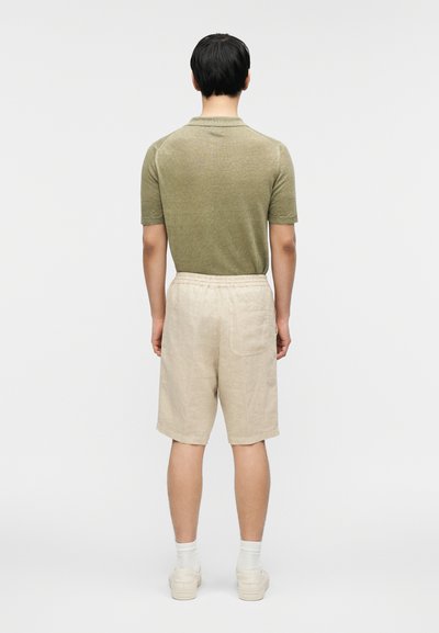 Πράσινο πουκάμισο με κοντά μανίκια και υφή, σε συνδυασμό με μπεζ λινά σορτς με ελαστική μέση και πίσω τσέπη.
