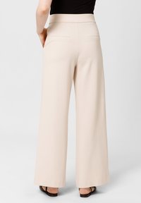 Spodnie o szerokich nogawkach w jasnym beżu, z wysokim stanem, gładkim materiałem i dwiema tylnymi kieszeniami. Minimalistyczny design z czystymi liniami.