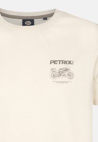 Cremefarvet bomulds t-shirt med grafisk design af en motorcykel og ordet "PETROL" i fed skrift. Klassisk crew neck med korte ærmer.