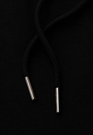 Un hoodie noir avec une paire de cordons noirs terminés par des embouts métalliques argentés sur un fond en tissu noir uni.