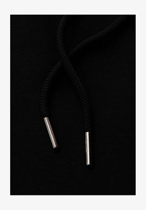 Sudadera negra con un par de cordones negros con puntas metálicas plateadas sobre un fondo de tela negra sólido.