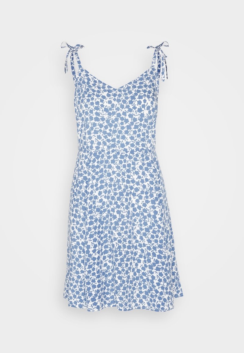 Robe blanche sans manches avec imprimé floral bleu, bretelles nouées réglables aux épaules et jupe évasée.