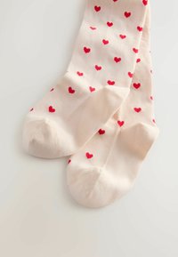Light beige socks with a ribbed texture, featuring a repeating pattern of small red hearts. Rounded toes and reinforced heels.