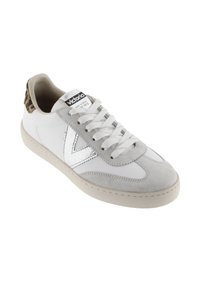 Zapatilla blanca hecha de cuero y ante, con un logo plateado, detalles en gris y una tapa de talón con estampado de leopardo. Diseño con cordones y suela de goma.