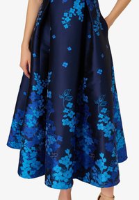 Blauer, floral bestickter Rock aus Satin mit einer dunkelblauen Grundfarbe, strukturierter Form und auffälligen blauen Mustern am Saum.