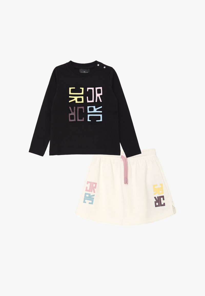 Maglietta nera a maniche lunghe con lettere geometriche multicolori; gonna bianca con vita elastica e dettagli pastello. Entrambi i capi sono realizzati in tessuto morbido.