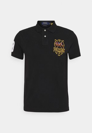 Svart pikétröja i bomull med en broderad gul emblem på bröstet och en vit siffra "8" på ärmen. Klassisk passform.