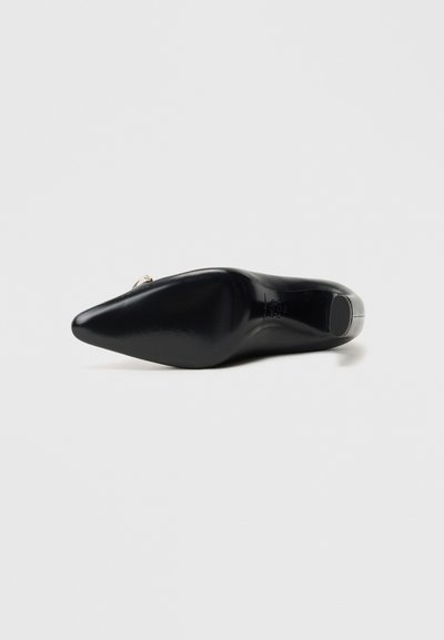 Zwarte hoge hak schoen met een spitse neus en glanzende lakleer textuur, met een subtiele metalen accent op de hak.