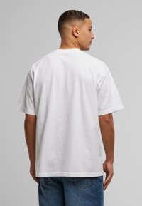 Hvit bomulls T-skjorte med avslappet passform, korte ermer og rund hals. Stoffet ser jevnt ut uten synlige mønstre.
