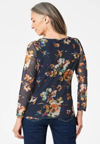 Blumenbedruckte Langarmbluse aus navyfarbenem Mesh mit mehrfarbigen Blumenmustern. Mit Rundhalsausschnitt und enganliegenden Ärmeln.