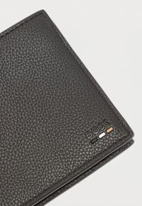 Zwarte leren portemonnee met korrelige textuur, voorzien van een geperst "BOSS"-logo en drie kleuraccenten: zwart, wit en koper.