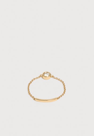 Bague chaîne en or délicate avec une petite pierre précieuse ronde claire et un accent barre lisse en or sur fond blanc.