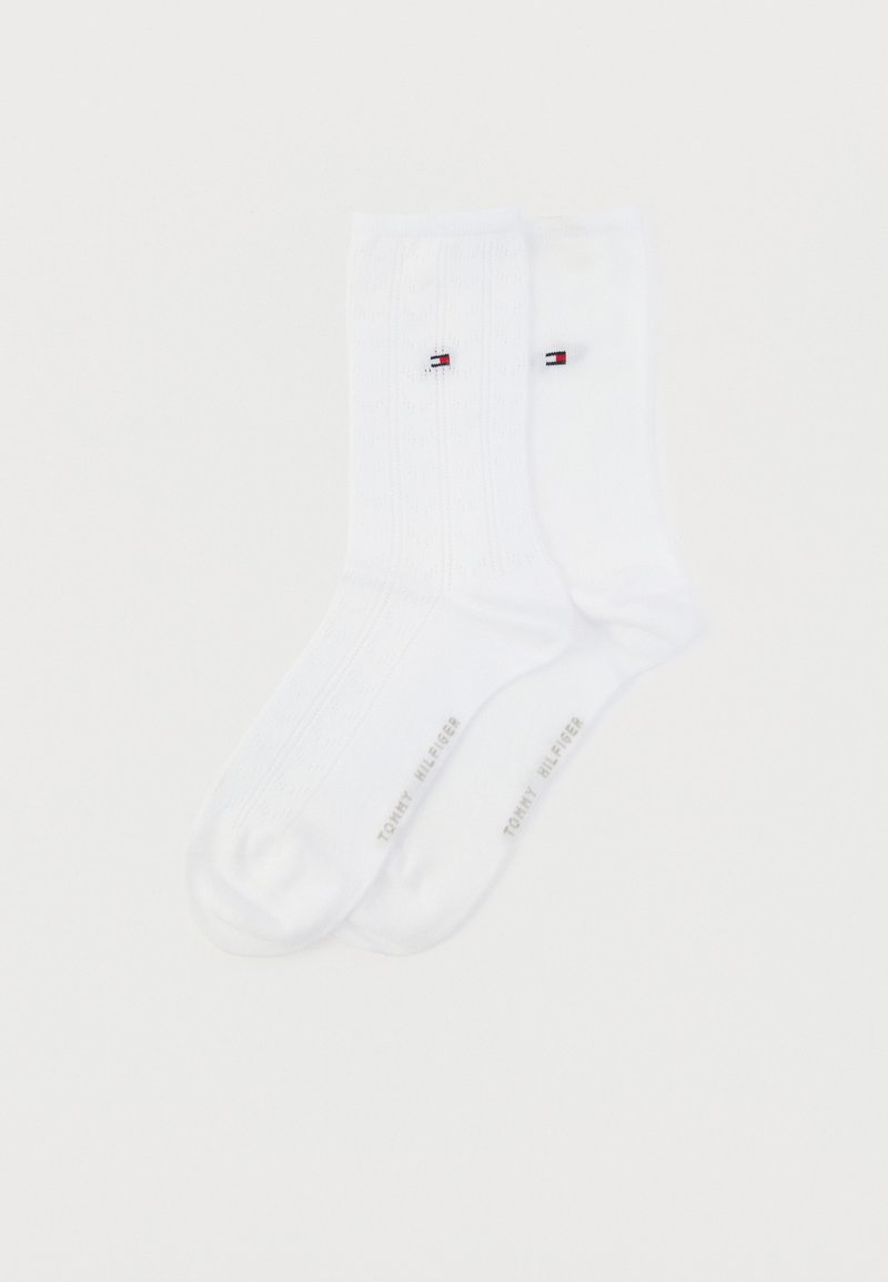 Άσπρες βαμβακερές κάλτσες με υφασμένες κατακόρυφες ρίγες, διαθέτοντας ένα μικρό λογότυπο σε κόκκινο, άσπρο και μπλε. Ενισχυμένη φτέρνα και μύτη, με το εμπορικό σήμα "TOMMY HILFIGER".