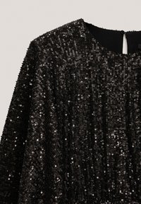 Svart paljettklänning med rund halsringning, med en texturerad yta av tätt packade paljetter och en subtil lyster.