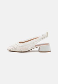 Escarpins blancs en dentelle avec un bout pointu, un motif floral texturé, un petit talon bloc et un accent frangé doux à l'arrière.