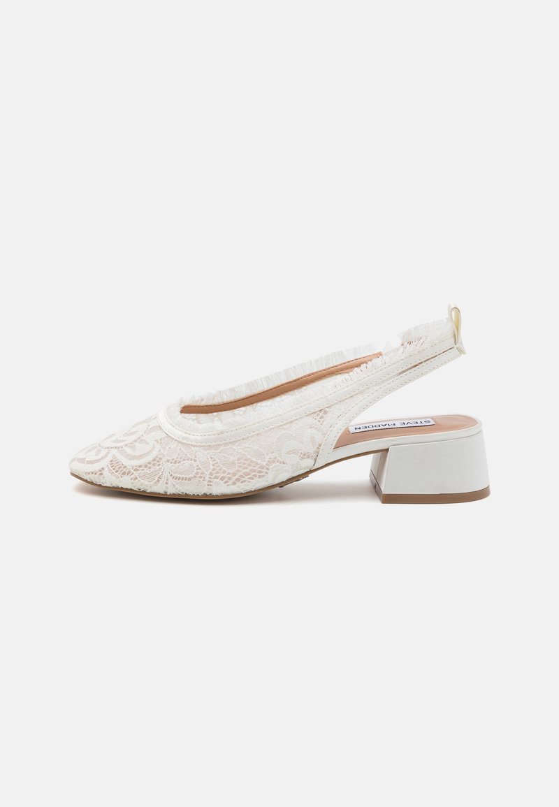Escarpins blancs en dentelle avec un bout pointu, un motif floral texturé, un petit talon bloc et un accent frangé doux à l'arrière.