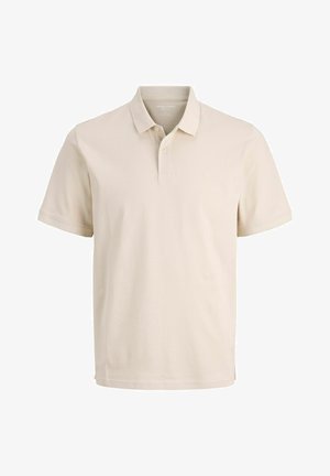 Beige polo paita tehtud puuvillast, lühikeste varrukatega, kahe nupuga kaelus ja rindkere peen logo. Sile tekstuur.