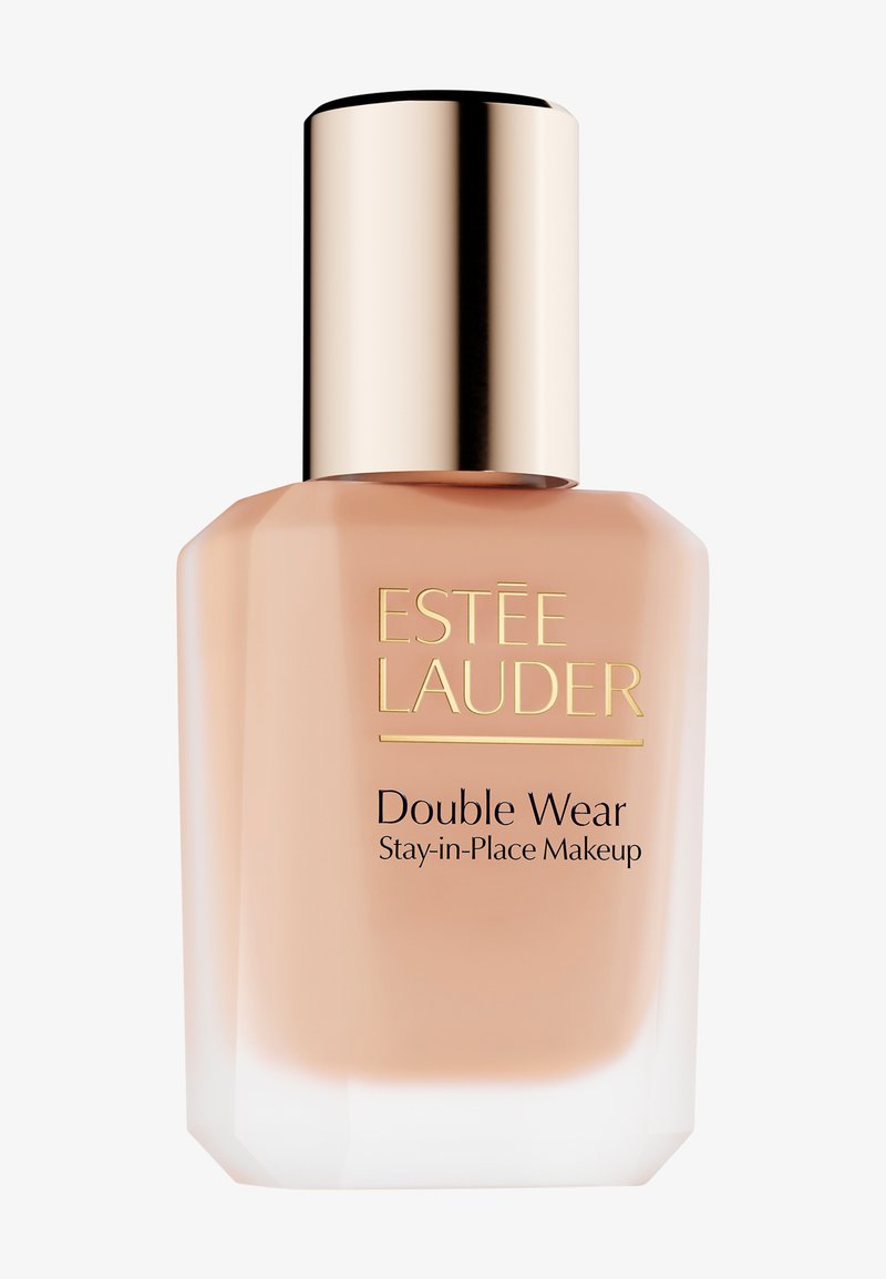 Estee Lauder Double Wear foundation in a clear glass bottle with a light peach hue, gold cap, and black text on the front.