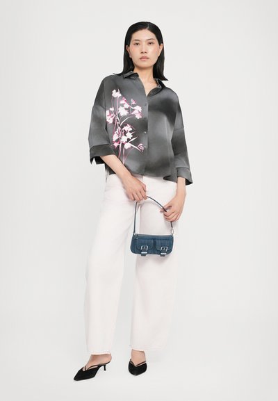 Bluză din mătase gri cu un design floral roz, cu mâneci largi, asortată cu pantaloni largi albi și o mică geantă din denim albastru. Pantofi cu toc negri.