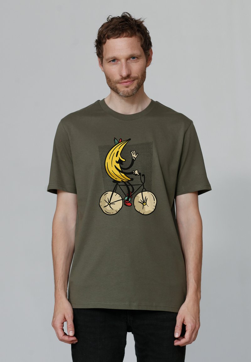 Olivegrünes Baumwoll-T-Shirt mit einem grafischen Design eines Bananen, die ein Fahrrad fährt, in kräftigen Farben und verspielten Details.