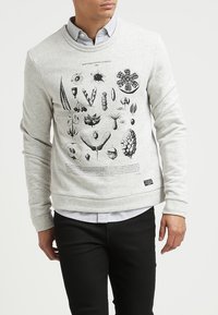 Sudadera gris con cuello redondo, con un gráfico negro detallado de diversas ilustraciones botánicas en la parte delantera.
