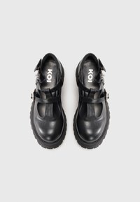 Črne usnjene čevlje s izrezljanim dizajnom, dvema zaponkama in strukturiranim gumijastim podplatom. Vsebujejo logo na podplatu in nastavljive trakove.