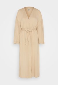 Beżowa sukienka typu wrap z dekoltem w kształcie litery V, bufiastymi rękawami i wiązanym w talii pasem. Wykonana z miękkiego materiału o gładkiej fakturze; długość do kolan, z minimalnymi detalami.